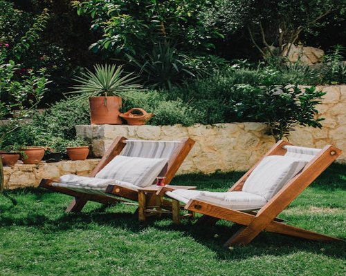 A serene view of a Mediterranean garden with a comfortable chair for resting